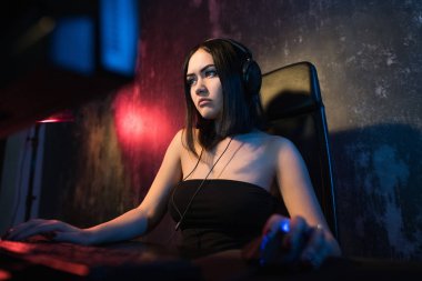 Güzel dost Pro Gamer kız yapar Video oyunu oyun akışı, giyen kulaklık görüşmeler ve kulaklık mikrofon içine onun hayranları ve takım ile sohbetler. Gençler eğleniyor. Arka plan Neon Retro renkleri
