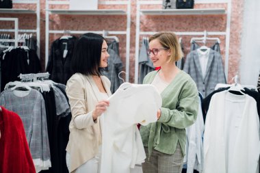 Güzel kızlar giysiler seçmek, söz ve butik alışveriş yaparken gülümseyen