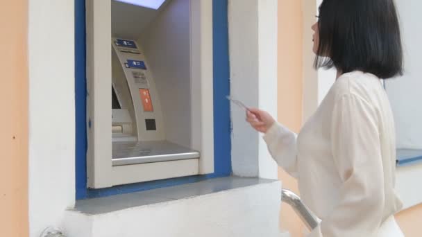 Молодая женщина вставляя кредитную карту в банкомат, красивая девушка банкинг, деловая женщина после работы в банке, торговый центр — стоковое видео
