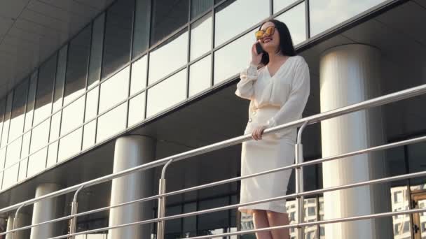 Mujer de negocios frente al edificio de oficinas hablando por teléfono celular — Vídeos de Stock