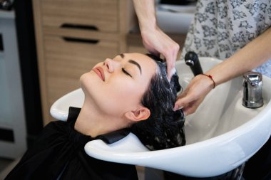 Güzel esmer saçlı bir güzellik salonu yıkar.