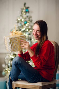 Gülümseyen güzel kadın Noel ağacı üzerinde arka plan üzerinde oturan