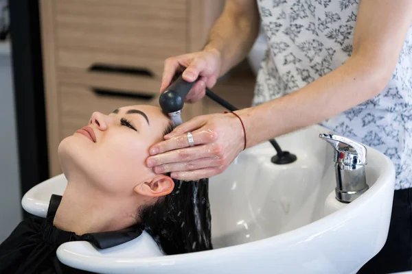 Kadeřnický salon. Krásná bruneta žena při mytí vlasů — Stock fotografie