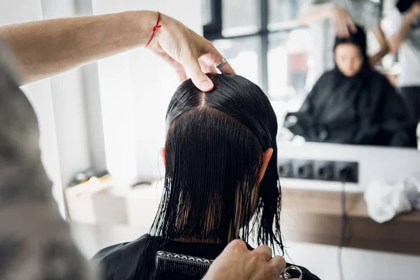 Tangan Mans dipotong dan menyisir perempuan berambut cokelat gelap di salon kecantikan dengan cermin — Stok Foto