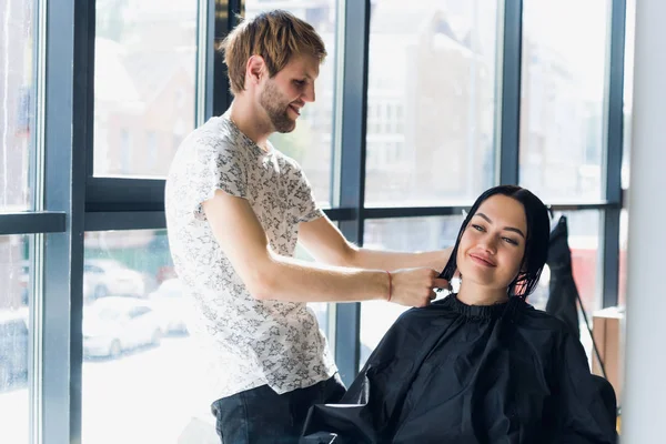 Професійний перукар, стиліст розчісує волосся жіночого клієнта в професійному перукарні. концепція краси та догляду за волоссям — стокове фото