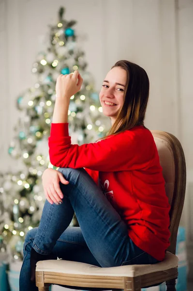 Ευτυχισμένη νεαρή γυναίκα που κάθεται κοντά στο χριστουγεννιάτικο δέντρο. — Φωτογραφία Αρχείου