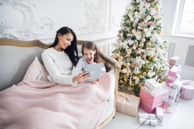 Güzel genç bir kadın ve kızı Noel zamanı elinde tabletle. Yakın plan..