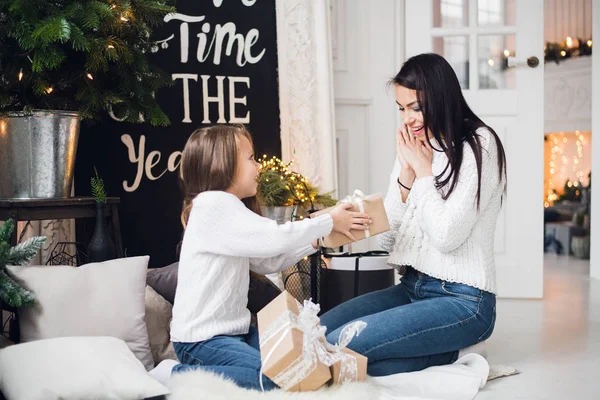 Joyeux Noël et Joyeuses Fêtes. Joyeux maman et sa fille mignonne fille ouvrant un cadeau de Noël. Parent et petit enfant s'amusent près de l'arbre de Noël à l'intérieur — Photo