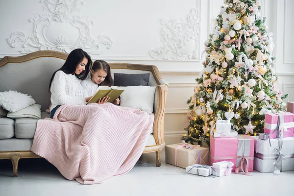 Mãe e sua filha lendo um livro no Natal — Fotografia de Stock