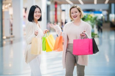 Alışveriş torbaları alışveriş merkezinde yürüyen iki mutlu arkadaşlar kızlarla