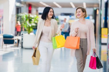 Mutlu holding alışveriş torbaları eğleniyor konuşurken kadınlar alışveriş gülüyor. Alışveriş merkezinde iki güzel genç kadın kız arkadaşım