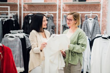 Güzel kızlar giysiler seçmek, söz ve butik alışveriş yaparken gülümseyen