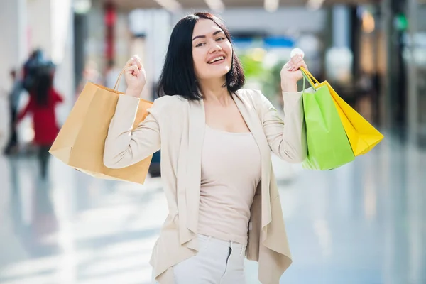 음소거, 부드러운 색상을 입고 검은 머리 여자 다채로운, 꽃무늬 쇼핑백 산책 전용 쇼핑몰에서 보유 하. — 스톡 사진
