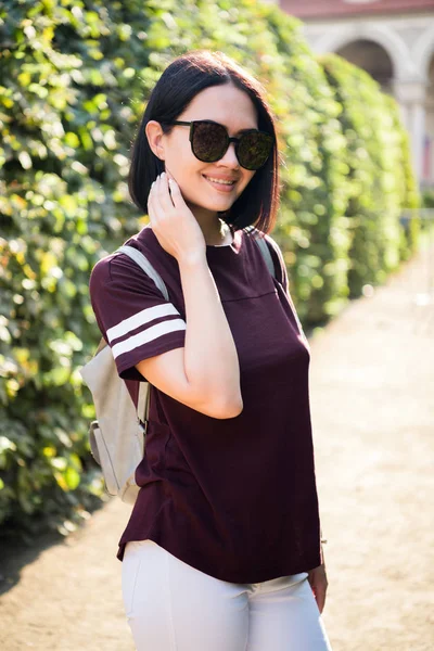 Close-up estilo de vida retrato de moda da jovem mulher hipster andando no parque, viajar com mochila, roupa casual elegante, pôr do sol da noite, refletindo estudante óculos de sol . — Fotografia de Stock