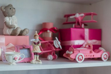 Noel hediyeleri bir rafta, pembe araba, uçak, ahşap at ve zencefilli çan.