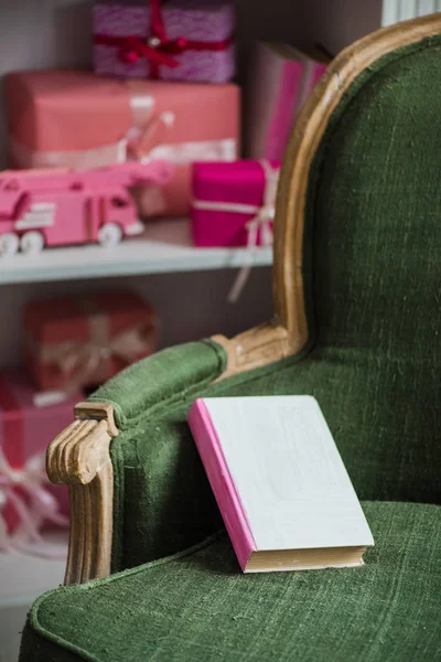 Haza karácsonyra. A fotel könyv és ajándékok a háttérben. — Stock Fotó
