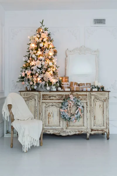 Albero di Natale su cassettiera in legno comò scrivania in bianco interno, decorato con fiori artificiali, ghirlande e giocattoli — Foto Stock
