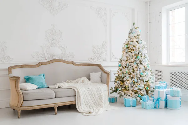 Stílusos karácsonyi belső, elegáns kanapéval. Kényelem otthon. Ajándékok a fa alatt a nappaliban. — Stock Fotó