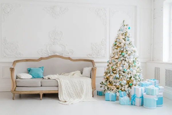 Stilvolles Weihnachtsinterieur mit elegantem Sofa. Wohnkomfort. Geschenke unterm Baum im Wohnzimmer — Stockfoto