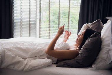 Onun cep telefonu kısa mesaj okuma ve gülümseyen güzel genç kadın.