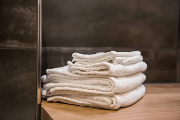 Toalhas de spa brancas empilhadas na mesa de madeira no banheiro moderno — Fotografia de Stock