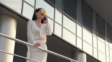 Beyaz gömlek ve siyah takım bina ve telefon konuşma iş karşı el demiryolu boyunca sokakta yürürken genç çekici işkadını