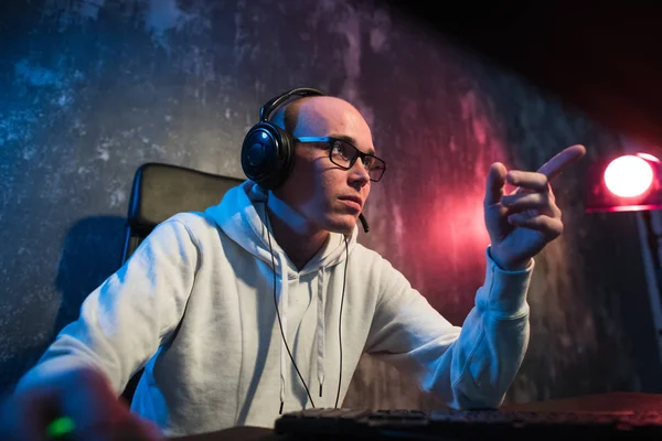 Joven jugador enojado en gafas de juego en el ordenador usando auriculares —  Fotos de Stock