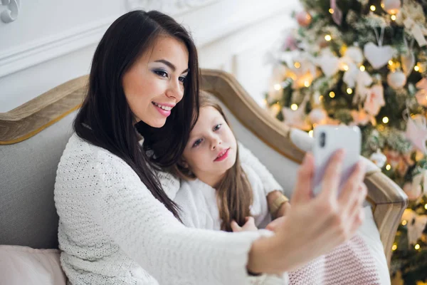Mano bien arreglada de una mujer sosteniendo un teléfono tomando una selfie con su hija, niña — Foto de Stock