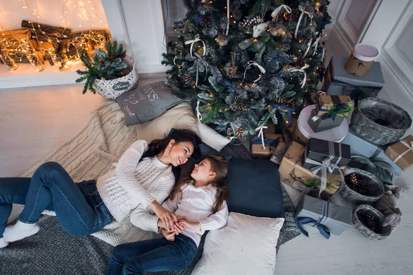 Feliz madre e hija abriendo regalos de Navidad. La familia se reunió alrededor de un árbol en casa. Árbol de Navidad con regalos debajo. sala de estar decorada —  Fotos de Stock