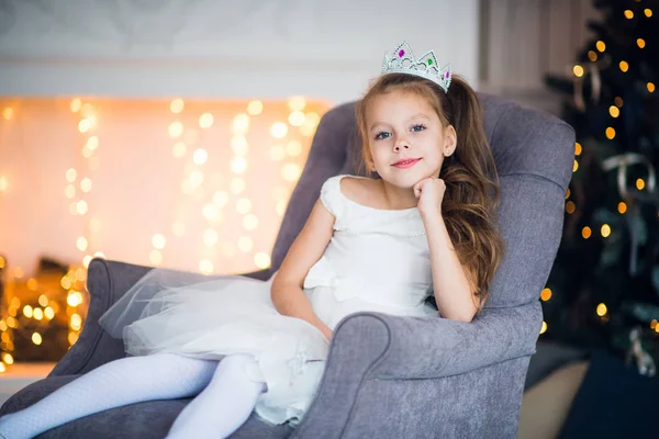 Mooi klein meisje zit in de fauteuil. Magie en feestelijke sfeer. — Stockfoto