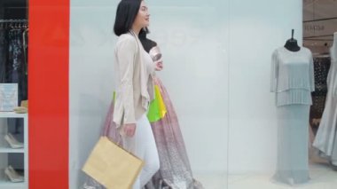 Alışveriş torbaları dükkanı penceresine bakarak çekici kadın