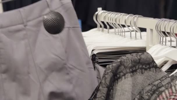 Gros plan, ralenti. La fille choisit des vêtements sur un cintre dans le magasin. Vêtements design, vêtements à la mode . — Video