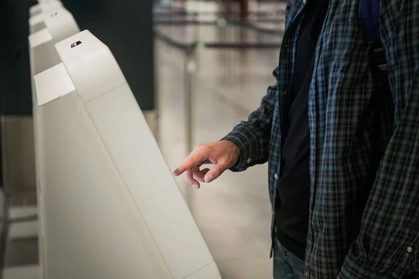 Jeune homme avec sac à dos tactile affichage interactif à l'aide de la machine libre-service, faire auto-enregistrement pour le vol ou acheter des billets d'avion à l'appareil automatique dans l'aérogare moderne — Photo
