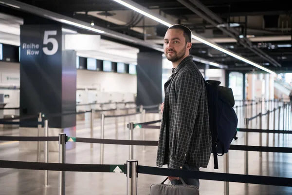 Ung man med hans bagage och ryggsäck med smartphone i väntan på flygbolaget flygning i internationella flygplats terminal, reser och online-incheckning begrepp — Stockfoto