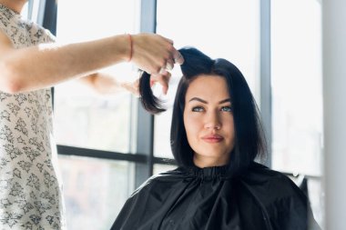 Profesyonel kuaför müşteri saç salonda ile çalışma. Bir tel çekme