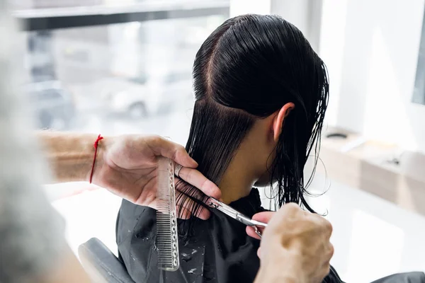 Cabeleireiro clientes corte de cabelo no salão com tesoura closeup. Usando um pente — Fotografia de Stock