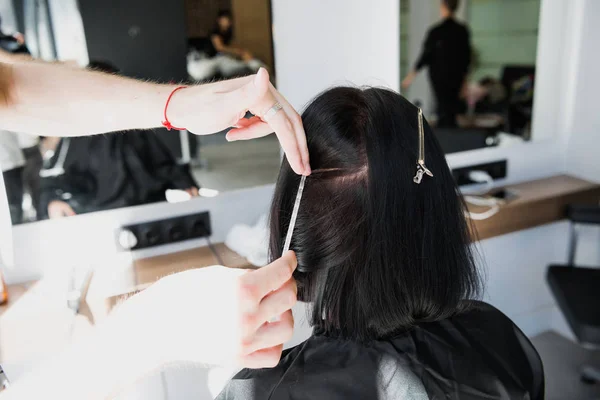 Κομμωτής εργάζεται με τα μαλλιά τους πελάτες στο σαλόνι. Τραβώντας ένα σκέλος — Φωτογραφία Αρχείου
