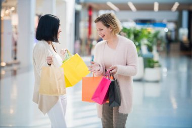 İki güzel genç kadın çantaları kontrol bir alışveriş merkezinde