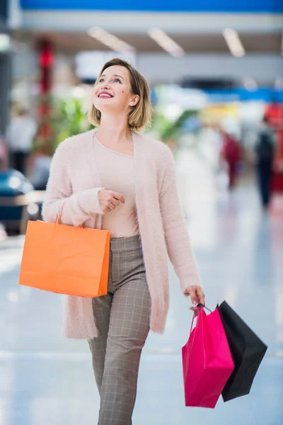 Fiatal boldog nő, sétál a mall bevásárló táskák — Stock Fotó