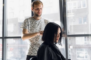 Güzel esmer kadın müşteri için genç erkek kuaför konuşurken bir güzellik salonunda gülmek. Güzel bir saç modeli yapma