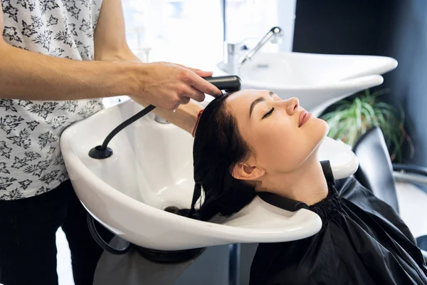 Salão de cabeleireiro. Mulher sente-se durante a lavagem do cabelo no salão . — Fotografia de Stock
