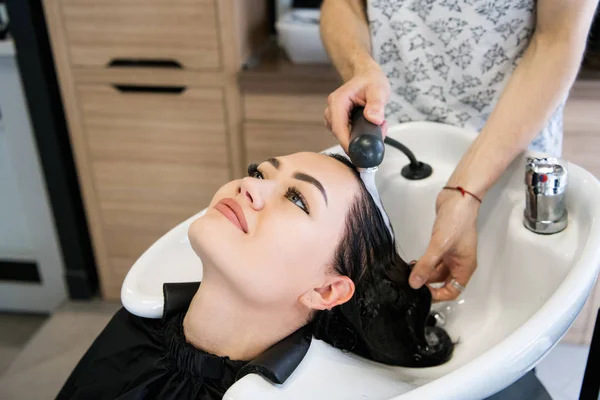 Парикмахерская. Красивая брюнетка во время мытья волос — стоковое фото