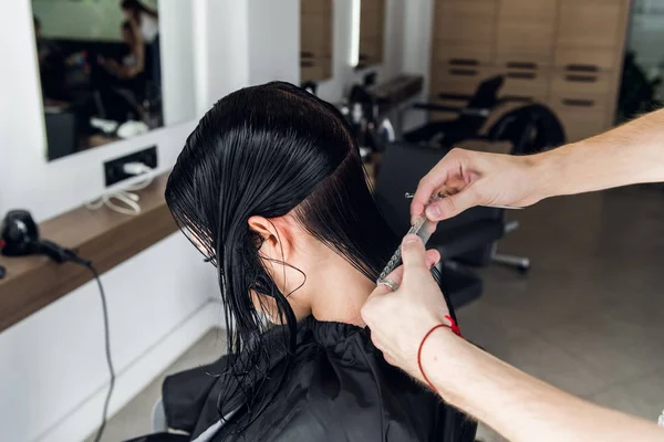 Penata rambut memotong rambut klien di salon dengan gunting penutup. Menggunakan sisir — Stok Foto