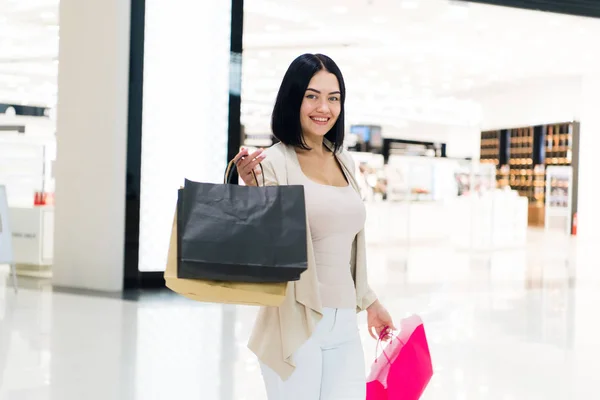 Счастливые молодые женщины показывают сумку с покупками, распродажу, потребительство и концепцию людей. Модный тон. Современный торговый центр — стоковое фото