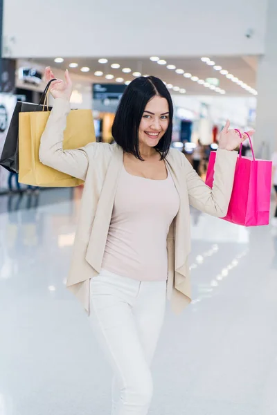 Портрет счастливой молодой женщины с сумками на аллее торгового центра — стоковое фото