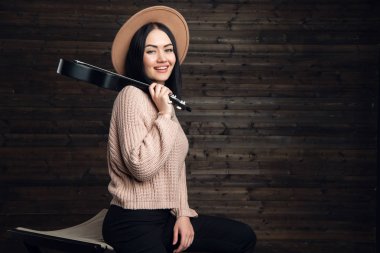 Çekici duygusal genç beyaz bir kadın kazak ve ukulele oynarken şapka. Güzel bir kadın şarkıcı kapalı müzik aleti çalma. İnsanlar, müzik, neşe ve eğlence