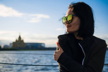 Nehir kenarında onu serbest zaman zevk güzel kadın. Kız açık hava yaşam tarzı. Güneş gözlüğü takıyor siyah saçlı Genç kadın.