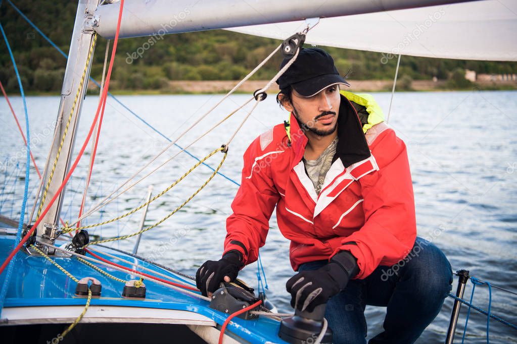 Yacht sailor pulling rope. Man working on sailboat.