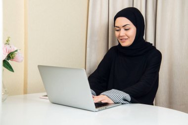 zarif çekici Müslüman kadın evde oturma odasında online alışveriş bilgi arama mobil dizüstü bilgisayar kullanarak