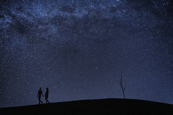 Silhouette of young couple under stars. The concept on the theme of love